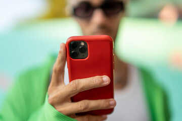 Chico sujetando smartphone con funda roja