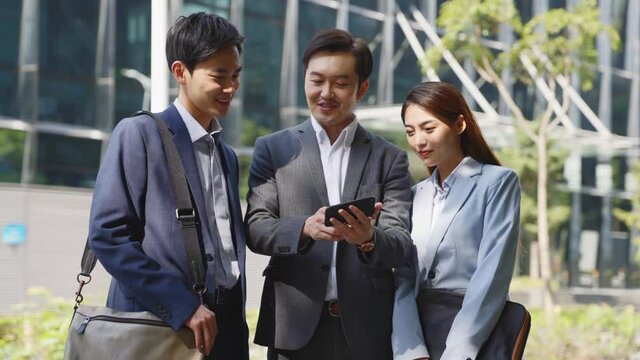 team of three asian corporate executive standing on downtown street discussing business in modern city