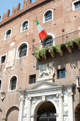 Portrait of an old municipal building in Tuscany showing the winged lion stonework and Italian flag above a balcony