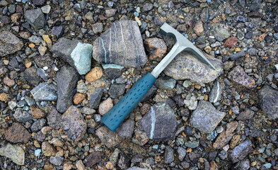 Steel geologists rock pick over background of multicolored serpentine rocks in asbestos mine - obrazy, fototapety, plakaty