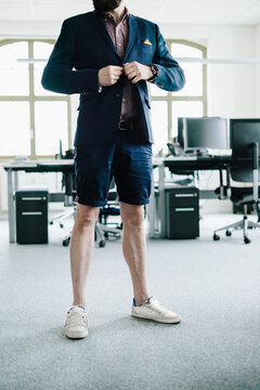 person in the office standing for desk in Shorts and blazzer