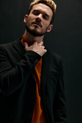 Obraz premium a blond guy in an orange sweater and a jacket holds his hand near his neck 