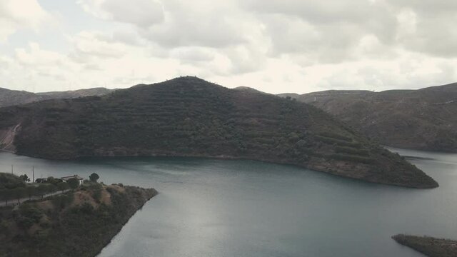 Aerial drone shot of natural Lake near Funcho de Diante during mystic cloudscape at sky after sunset. Rocky mountains surrounding calm water.