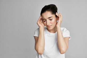 Woman in white t-shirt holding her head headache upset