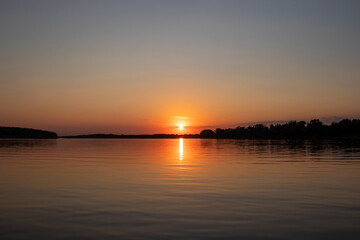 Red sunset on the river. Evening. The rays of the sun in the clouds