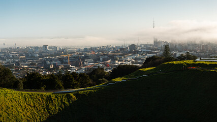 View from Mt Eden summit with fog drifting over Sky Tower and Auckland city