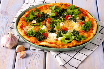 Pizza with with spinach, mozzarella, cherry tomatoes and garlic.