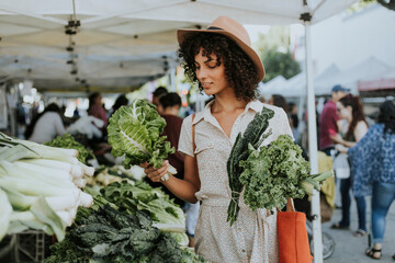 Beautiful woman buying kale at a farmers market - obrazy, fototapety, plakaty