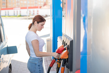 Caucasian woman refueling a car at a self-service gas station.