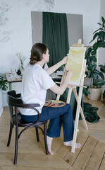 Creative entrepreneur. A young woman paints a picture in a spacious studio. Professional artist....