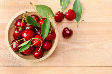 plate with fresh cherries on wooden background