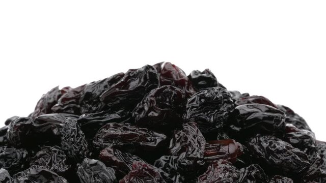 Close-up of black raisins rotating. Isolated on white background.
