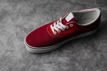 New pair of red sneakers isolated on dark background with copy space. Sport shoes lifestyle.