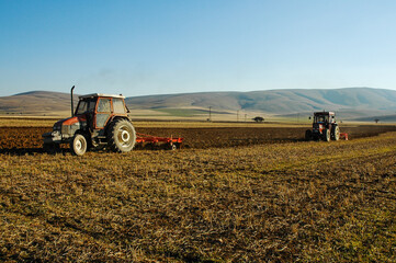 Obraz premium red tractor plows the field