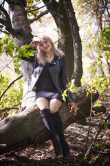 Sexy young woman in a little black dress and biker jacket relaxing in nature