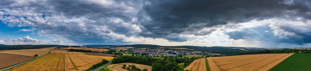 Bird's eye view over fields to a village in the Taunus / Germany with threatening thunderstorm clouds