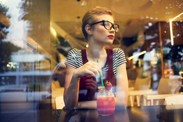 woman in glasses with short hair sits in a cafe loneliness cocktail rest