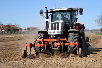 Fototapeta premium 11.30 Tuesday 30 March 2021. Hintergasse, Saulheim, Rhineland-Palatinate, Germany. Tractor Ploughing and sowing seeds onto an agricultural field on a sunny day at the start of the spring season. 