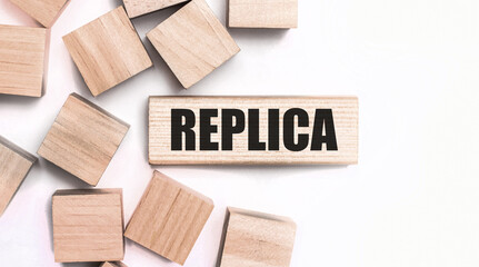On a light background, wooden cubes and a wooden block with the text REPLICA. View from above