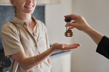 Close up of female real estate agent giving keys to young woman buying new house, copy space