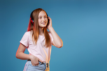 Cute teenager girl with red hair in wireless headphones