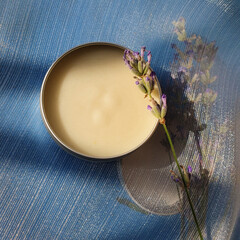 Jar with cream and lavender on a blue background.