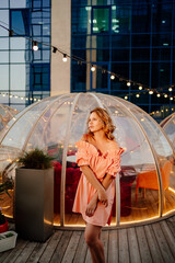 portrait of an attractive woman in a pink dress in a rooftop cafe