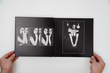 hands holding a open photobook from photo shoot of an woman on white background.