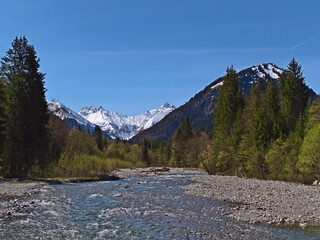 Beautiful landscape with the confluence of rivers Trettach and Oybach in the south of Oberstdorf, Bavaria, Germany in spring season with the snow-capped mountains of the Allgäu Alps on sunny day.