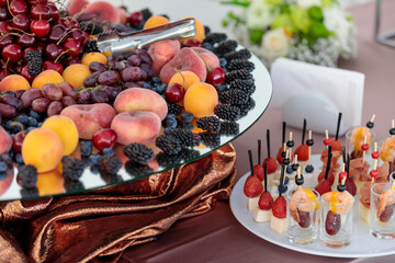 table with a variety of fruit snacks and berries. Buffet for a company dessert. Fresh cherries, strawberries, apricots