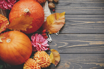 Happy Thanksgiving. Beautiful pumpkins, dahlias flowers, leaves and walnuts on rustic wooden background, flat lay with space for text. Seasons greeting card template. Autumn composition on table