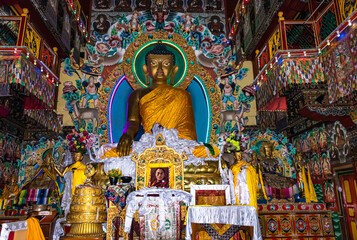huge buddha golden statue decorated with religious flags and offerings at evening - obrazy, fototapety, plakaty