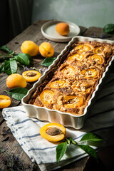 Apricot and frangipane tart in rectangular ceramic baking form on old wooden table.