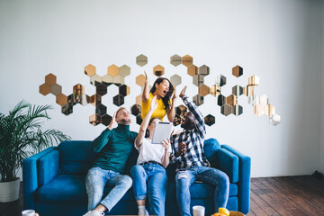 Naklejka premium Delighted multiethnic friends celebrating success in light office