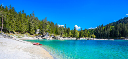 Boat on the shore of Cauma Lake (Caumasee) with crystal blue water in beautiful mountain landscape scenery at Flims, Graubuenden - Switzerland