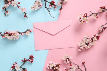 Envelope and beautiful flowering branches on pink blue background. Flat lay, top view.