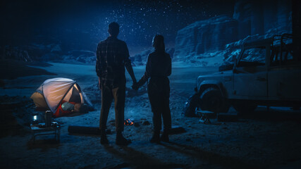 Happy Couple Camping in the Canyon at Night, Standing by Campfire, Holding Hands Lovingly and...