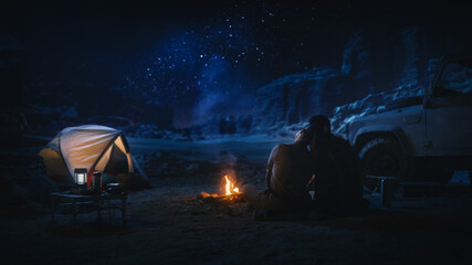 Happy Couple Camping in the Canyon, Sitting Watching Campfire and Starry sky Together, She Rests Her Head on His Shoulder. Two Traveling people On Inspirational Vacation Trip Marvel at Milky Way Stars