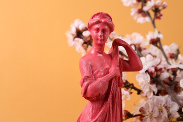 Godness sculpture and Beautiful flowering branches on orange background.