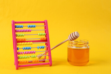Abacus with Bee honey jar and honey wooden spoon on yellow background