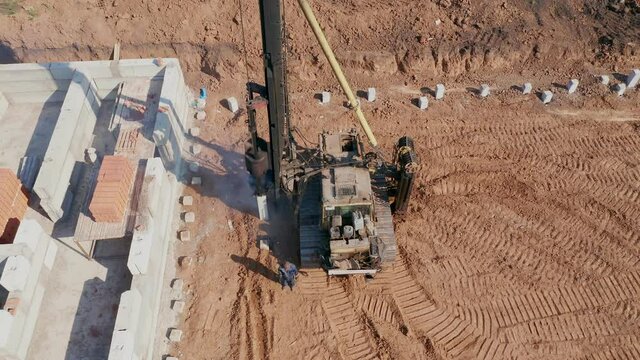 Construction of the main walls of a residential multi-storey building. A pile-driving machine, mechanized labor works on the site. Construction company. High quality. 4k footage.