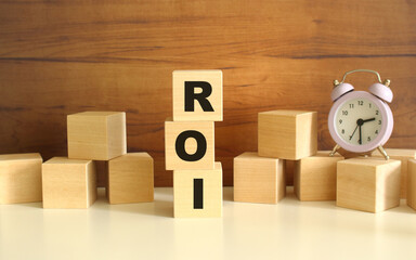 Three wooden cubes stacked vertically on a brown background make up the word ROI.
