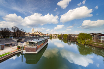 Wide sunset view of the Isle river with a barge or houseboat and the Saint Front cathedral in the background from the bridge Saint George. Perigueux, Dordogne Department, Nouvelle Aquitaine. France