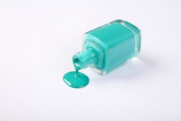 Bottle with blue spilled nail polish isolated on white background