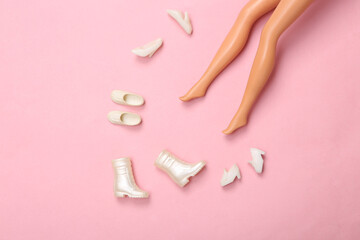 Doll feet chooses shoes on pink background. Minimalistic fashion layout