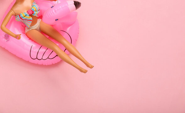 Doll in a swimsuit resting on inflatable flamingo. Summer vacation, beach party