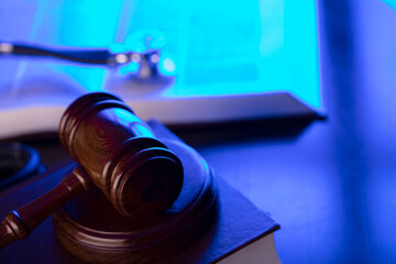 Medical law concept. Gavel, legal code and stethoscope on the glass table. Blue light.