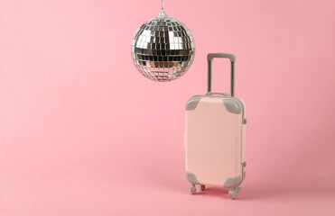 Disco ball and luggage on pink background. Minimalism party and travel concept
