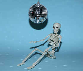Disco ball and skeleton on blue background. Minimalism party concept