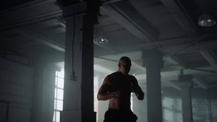Fototapeta na wymiar Kickboxer training in loft building. Athlete preparing for fight competition